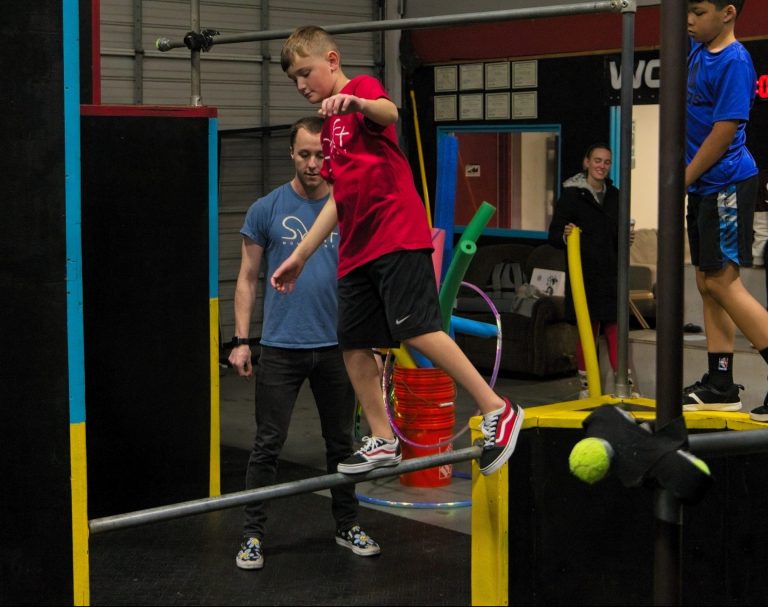 A Swift coach supports a child balancing on a rail