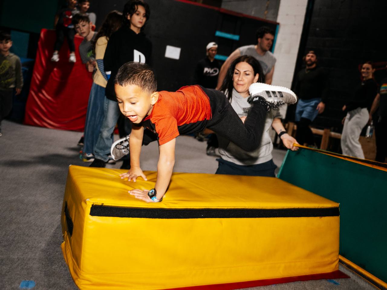 Pre-K student practicing parkour with coach support