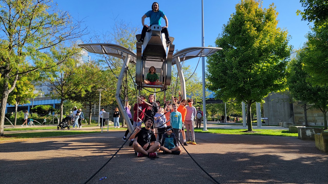 Children and adults gathered around a winged playground structure at CincyJam 2025.